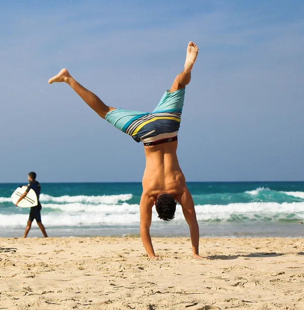 Person doing handstand on beach showing optimal health and active lifestyle